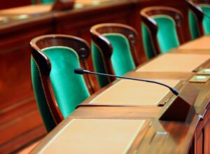Green upholstered seats and desk microphones in an empty congress hall.