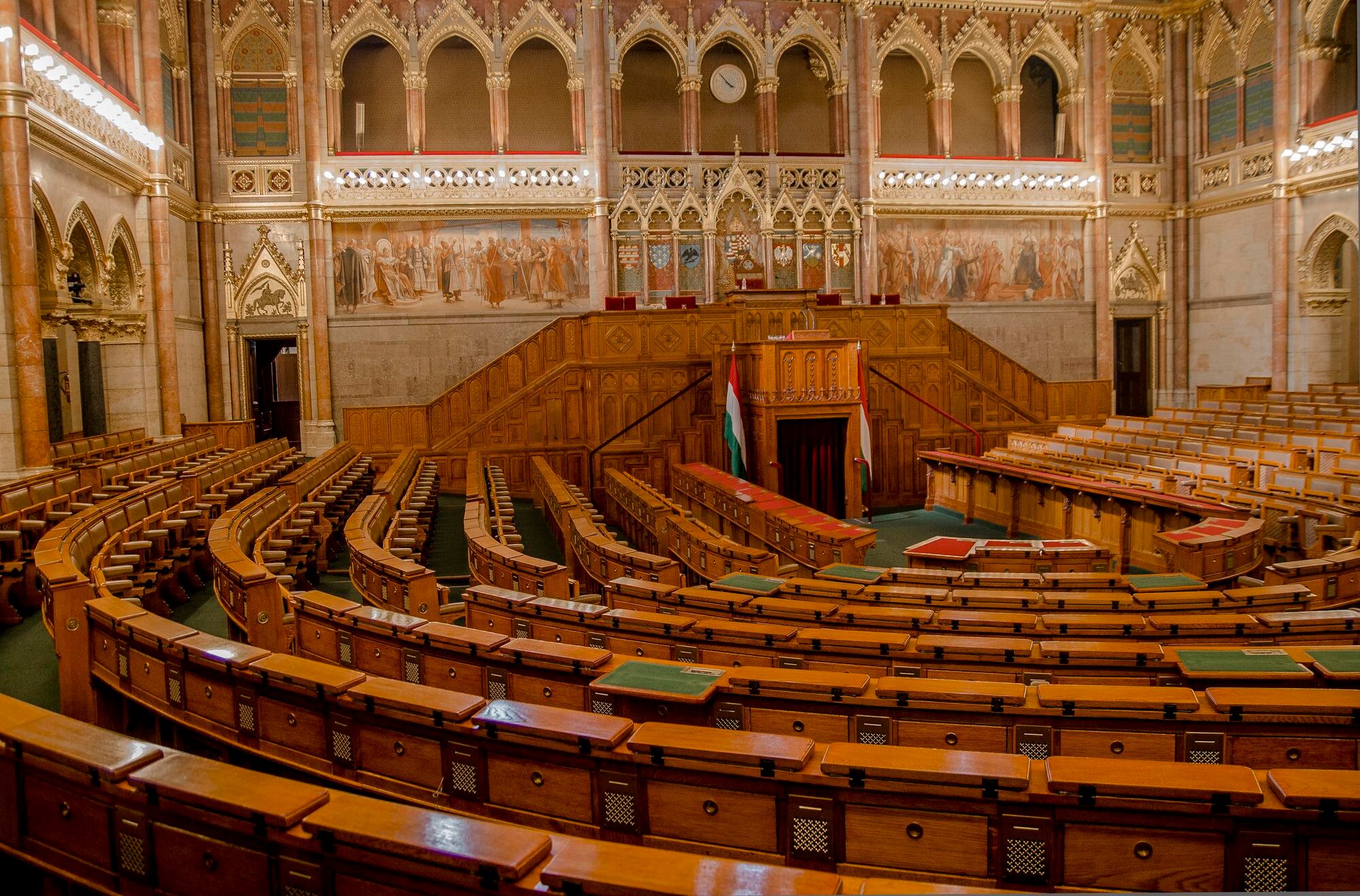 Rows of wooden benches inside the ornate parliamentary chamber in Budapest, Hungary.
