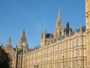 Gothic towers and ornate stonework of the Houses of Parliament beneath a clear blue sky.